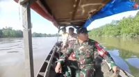 Gunakan Sampan Mesin. Bhabinkamtibmas dan Babinsa Susuri Anak Sungai Ciptakan Pilkada Damai